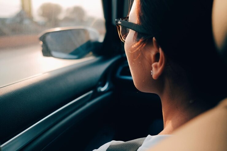 Photo of a person wearing glasses looking out the window of a car.