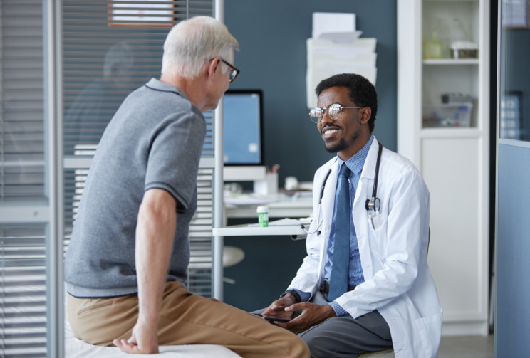 A photo of a patient on an examination table talking to a doctor.