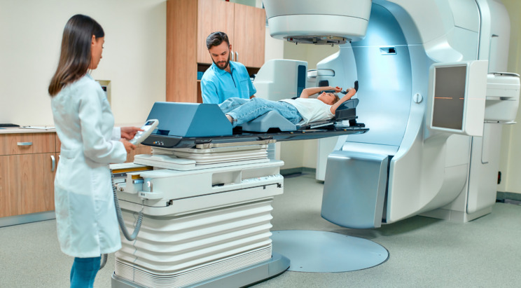 Photo of two healthcare professionals setting up a radiotherapy machine for a patient.