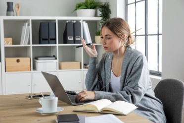 person sat at a desk with a laptop and files in the background